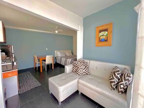 Un salon comprenant un canapé, un pouf et un coin repas avec une table et des chaises.