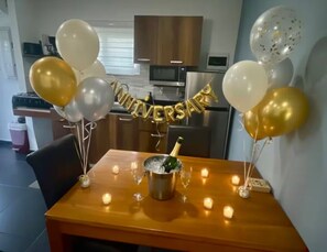 A dining table with a bottle of champagne, candles, and balloons. - Romantic King Studio w/ Private Jacuzzi Palm beach (Noord)
