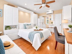 A bedroom with a bed, a desk, a chair, a ceiling fan, and a kitchenette. - Beachside Studio I Pool I Full Kitchen (Hollywood)