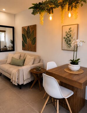 A modern living room with a sofa, a dining table with chairs, and artwork on the walls. - Private Patio Retreat • 3 Min to Palm Beach (Noord)