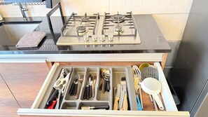 Una cocina con estufa a gas y organizador de cajones con utensilios.