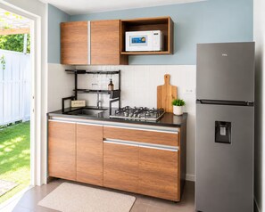A modern kitchen with wooden cabinets, a stainless steel refrigerator, a built-in microwave, and a gas stove. - Private Patio Retreat • 3 Min to Palm Beach (Noord)