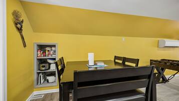 Un comedor con una mesa, sillas y un armario de cocina frente a una pared amarilla.