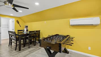 A room with a foosball table, a ceiling fan, and an air conditioning unit.