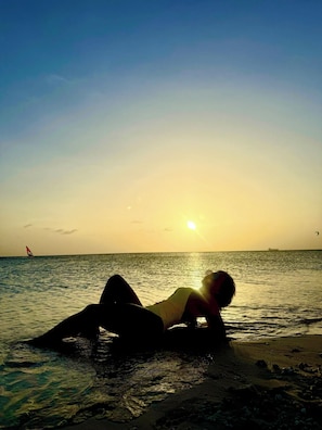 Una persona descansando en la playa al atardecer.