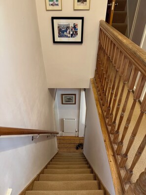A carpeted staircase with a wooden handrail, a white radiator, and a framed collage on the wall. - Gorgeous 3-bedroom townhome on Endcliffe Park (Sheffield)