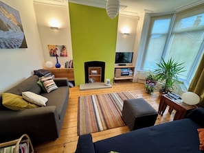 A living room with a sofa, a television, a fireplace, and a large window. - Gorgeous 3-bedroom townhome on Endcliffe Park (Sheffield)