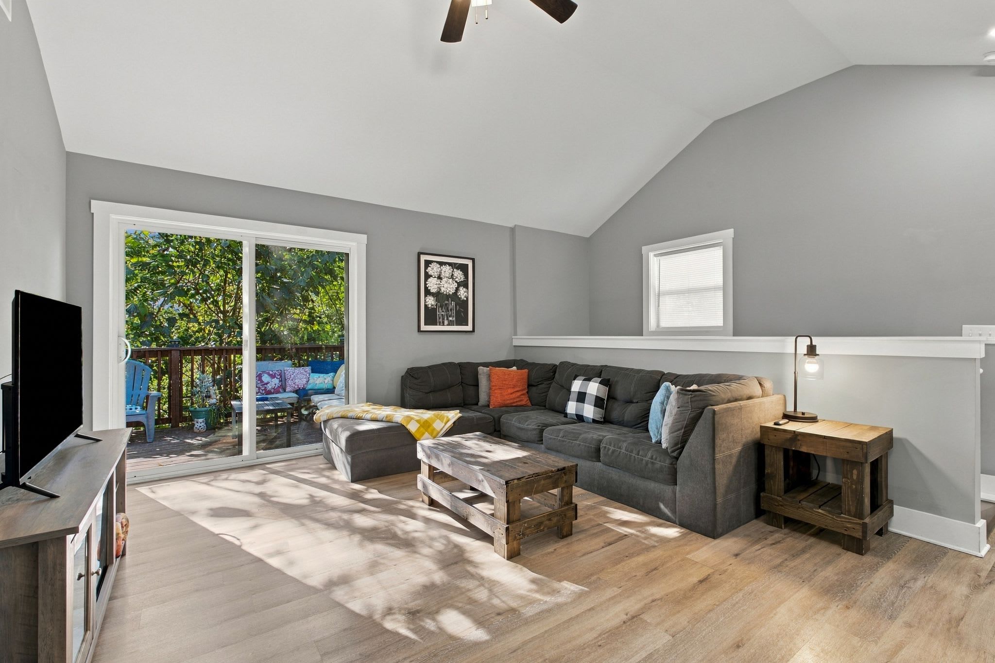 A modern living room with a grey sofa, a wooden coffee table, and a TV stand.