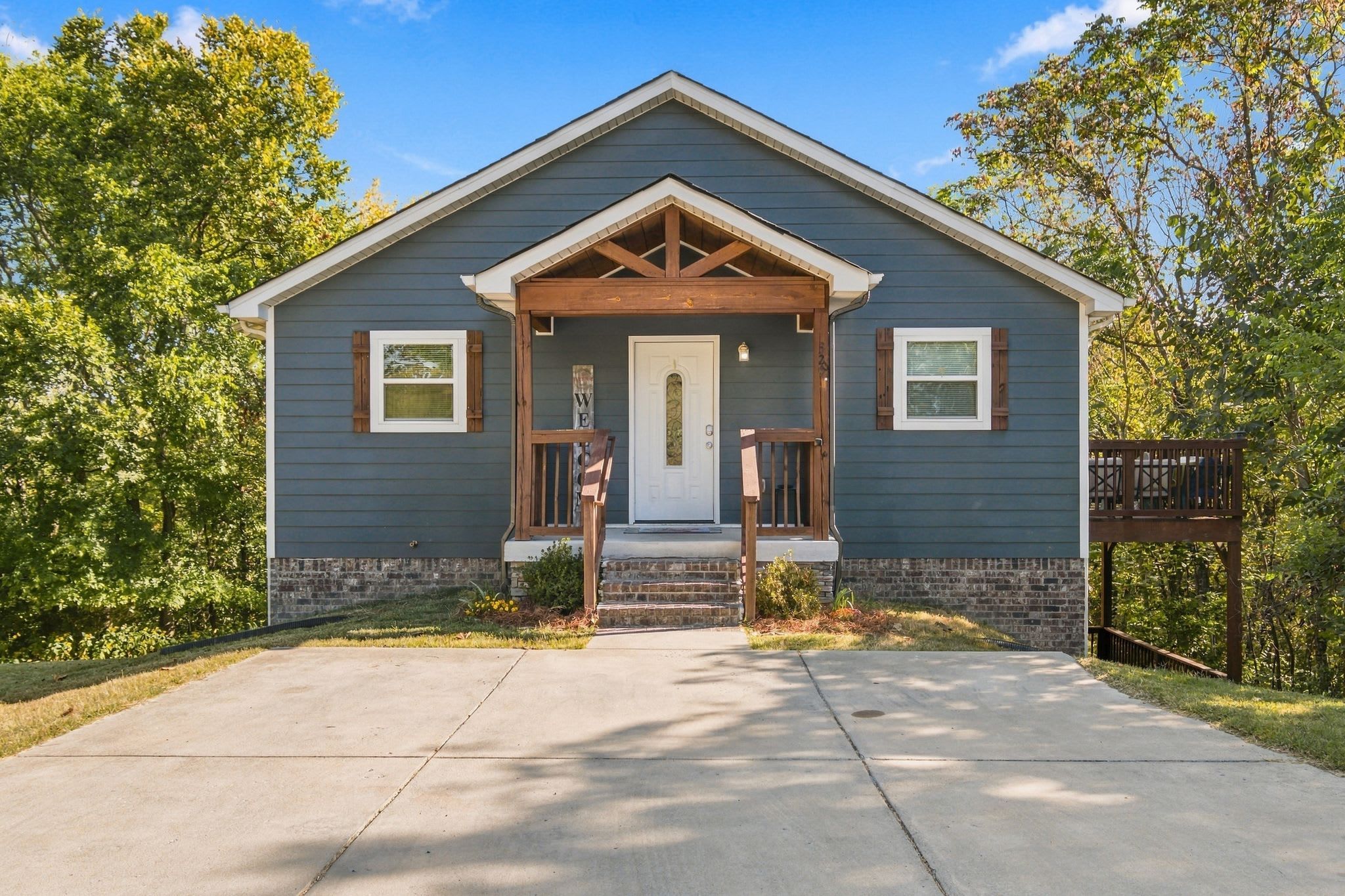 A two-story house with a front porch, a mailbox, and a small garden area.