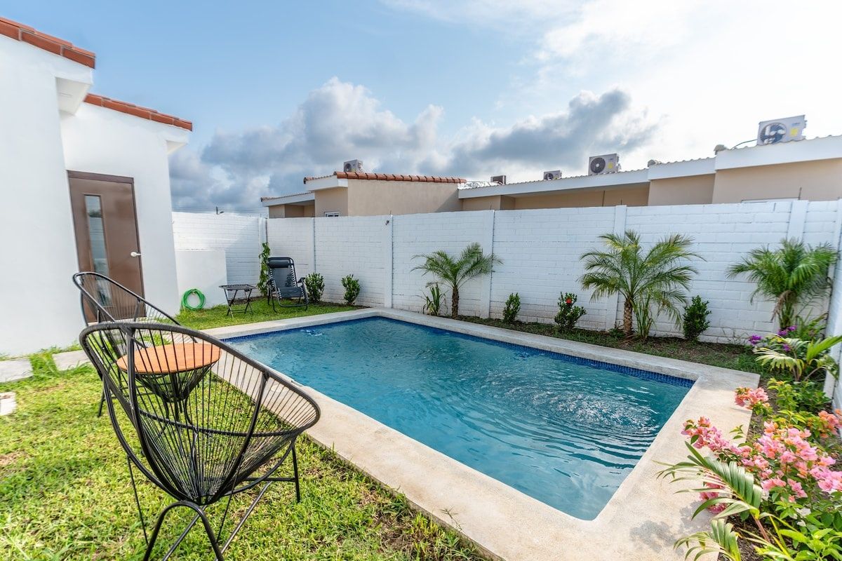 Una piscina con valla blanca, una silla y una puerta.