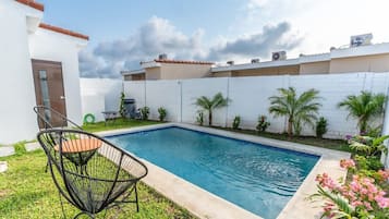 Una piscina con valla blanca, una silla y una puerta.