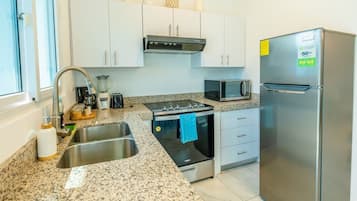 Una cocina moderna con electrodomésticos de acero inoxidable, encimera de granito y armarios blancos.