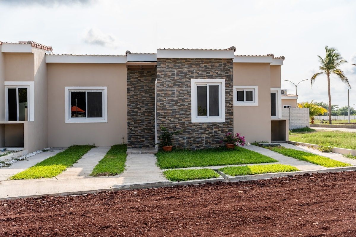 A modern two-story house with a stone facade, a front porch, and a well-maintained lawn.