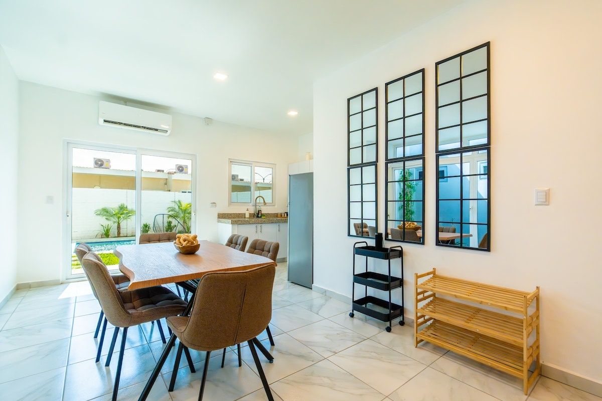 Una cocina moderna con comedor, ventanas amplias y vistas al exterior.