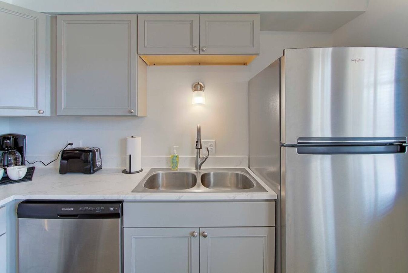 A modern kitchen with stainless steel appliances, a double sink, and a dishwasher.