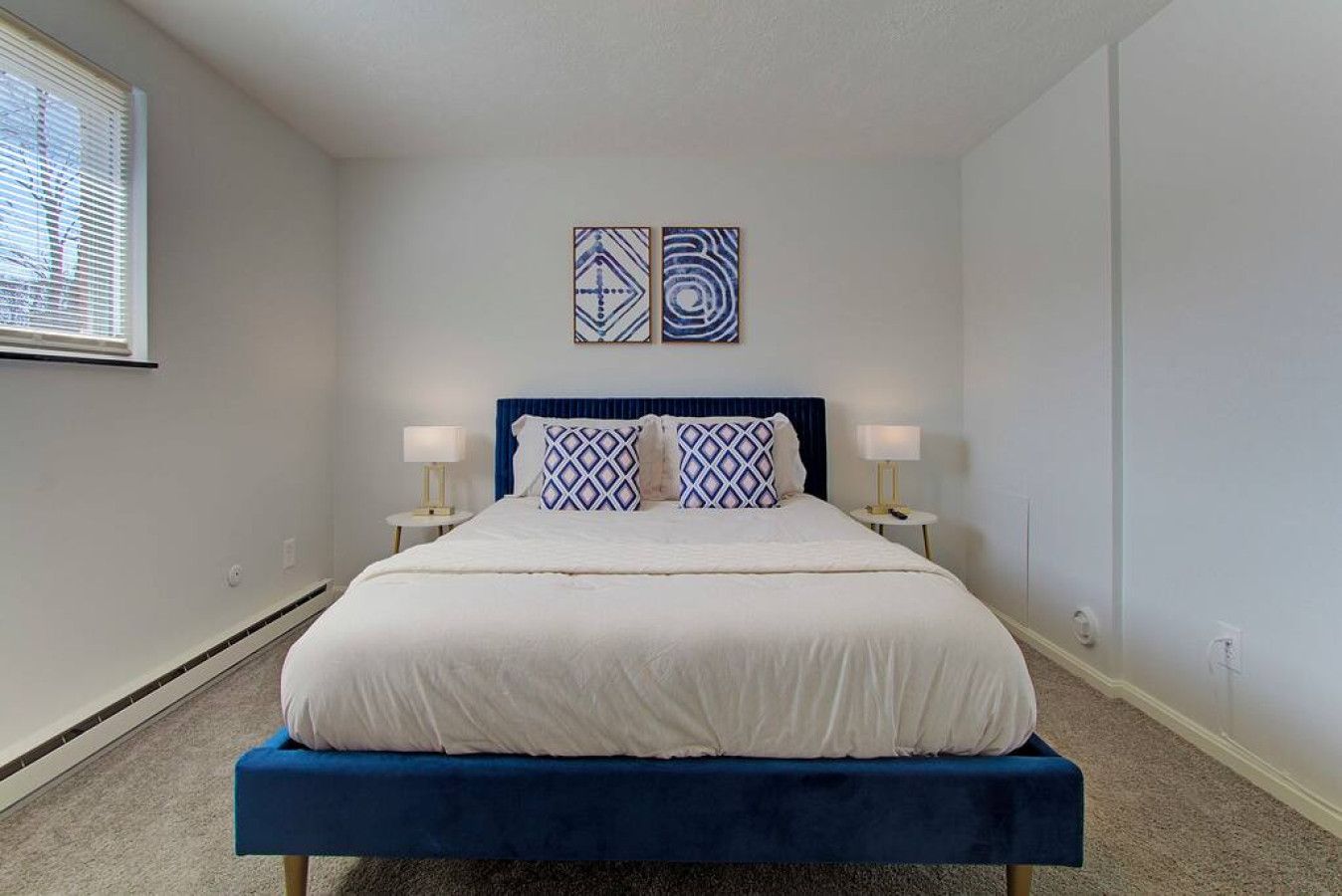 A bedroom with a bed, two bedside tables, and two wall-mounted artworks.