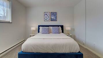 A bedroom with a bed, two bedside tables, and two wall-mounted artworks.