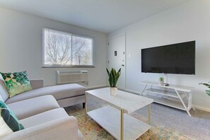 A modern living room with a sofa, coffee table, TV, and a plant.