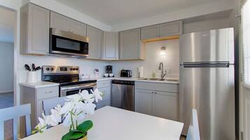 A modern kitchen with stainless steel appliances, white cabinetry, and a central island with a vase of flowers.