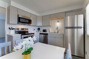 A modern kitchen with stainless steel appliances, white cabinetry, and a central island with a vase of flowers.