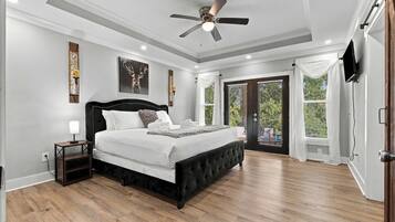A bedroom with a large bed, a ceiling fan, and a view of the outdoors through a sliding glass door.