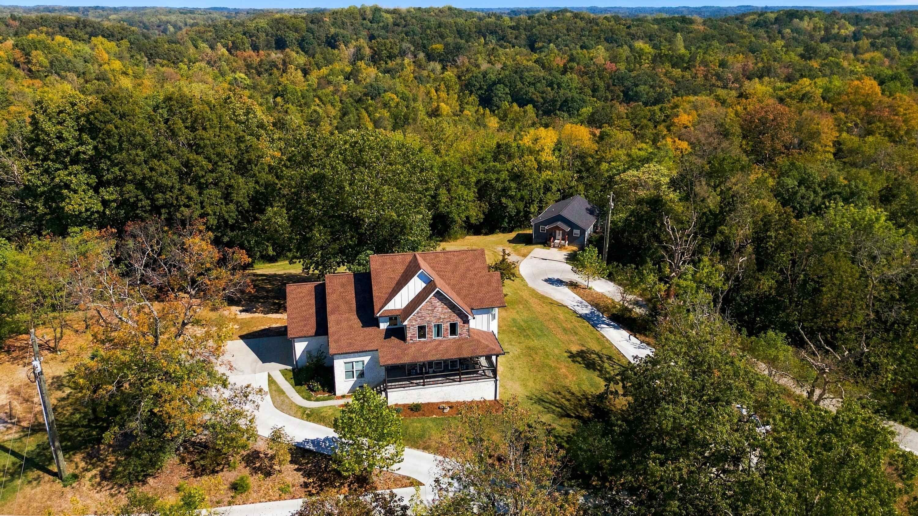 A two-story house with a large front porch and a driveway leading to a garage.