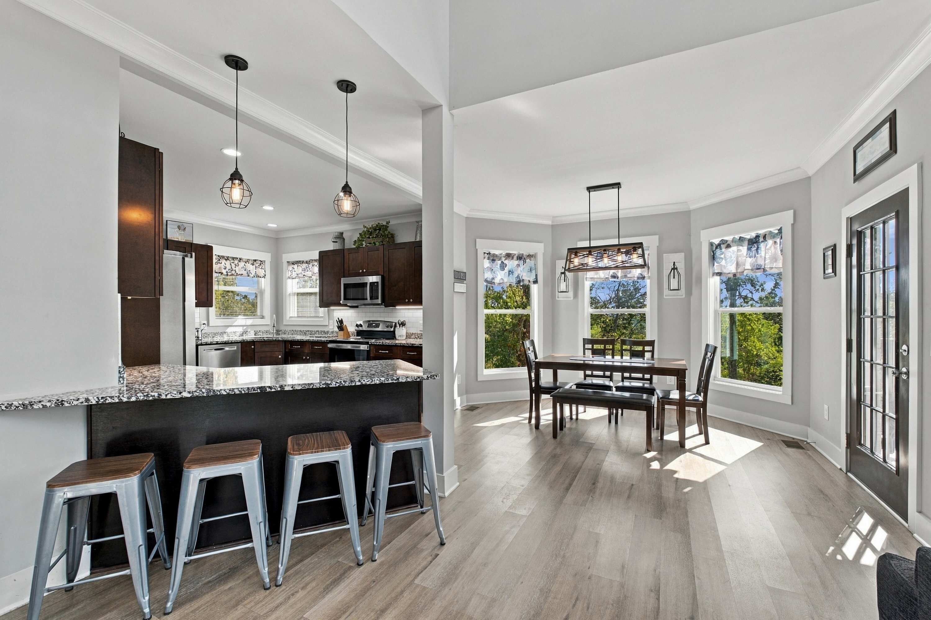 A modern kitchen with a central island, bar stools, and pendant lighting.