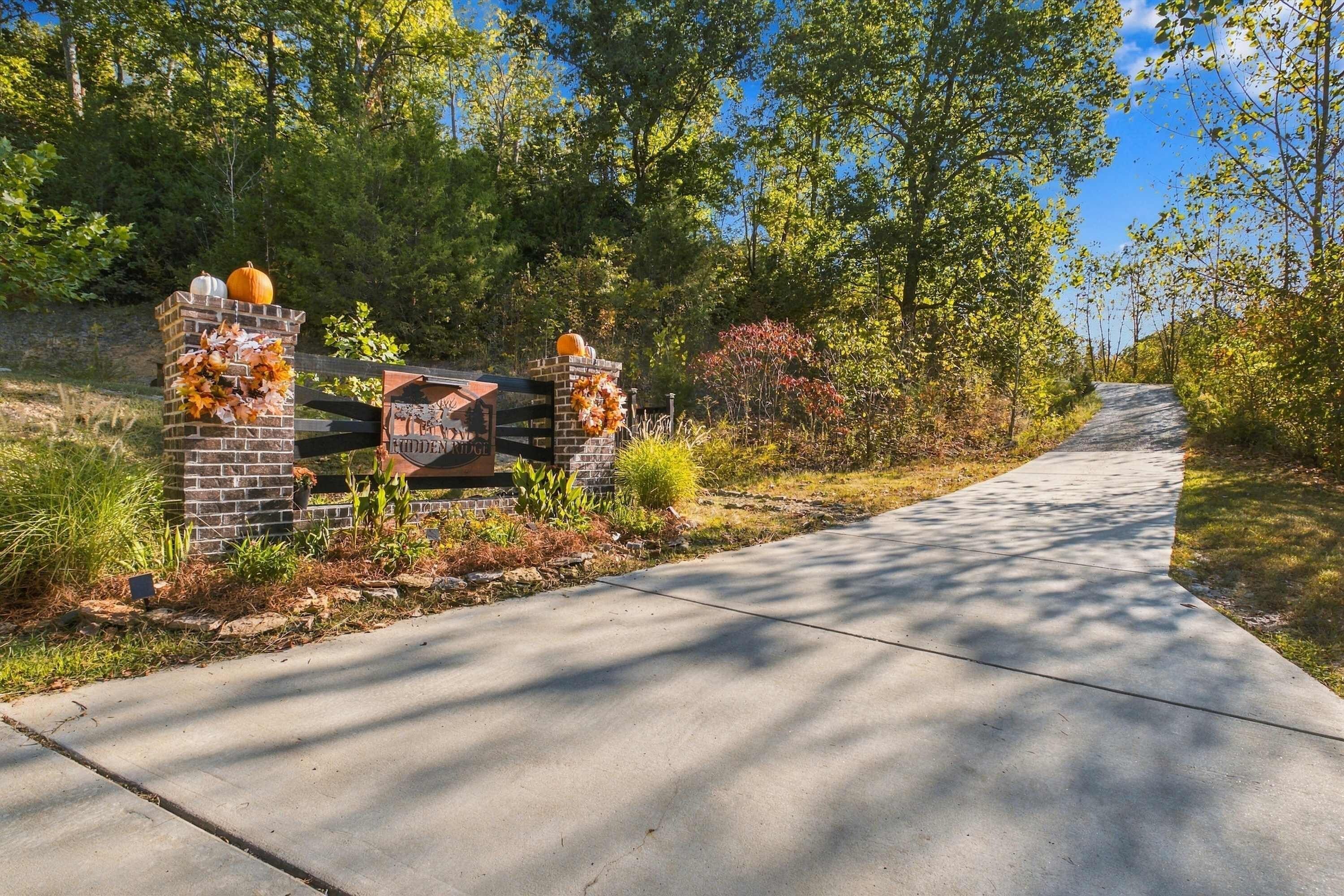 A paved pathway leading to a brick entrance with decorative autumn leaves and pumpkins.