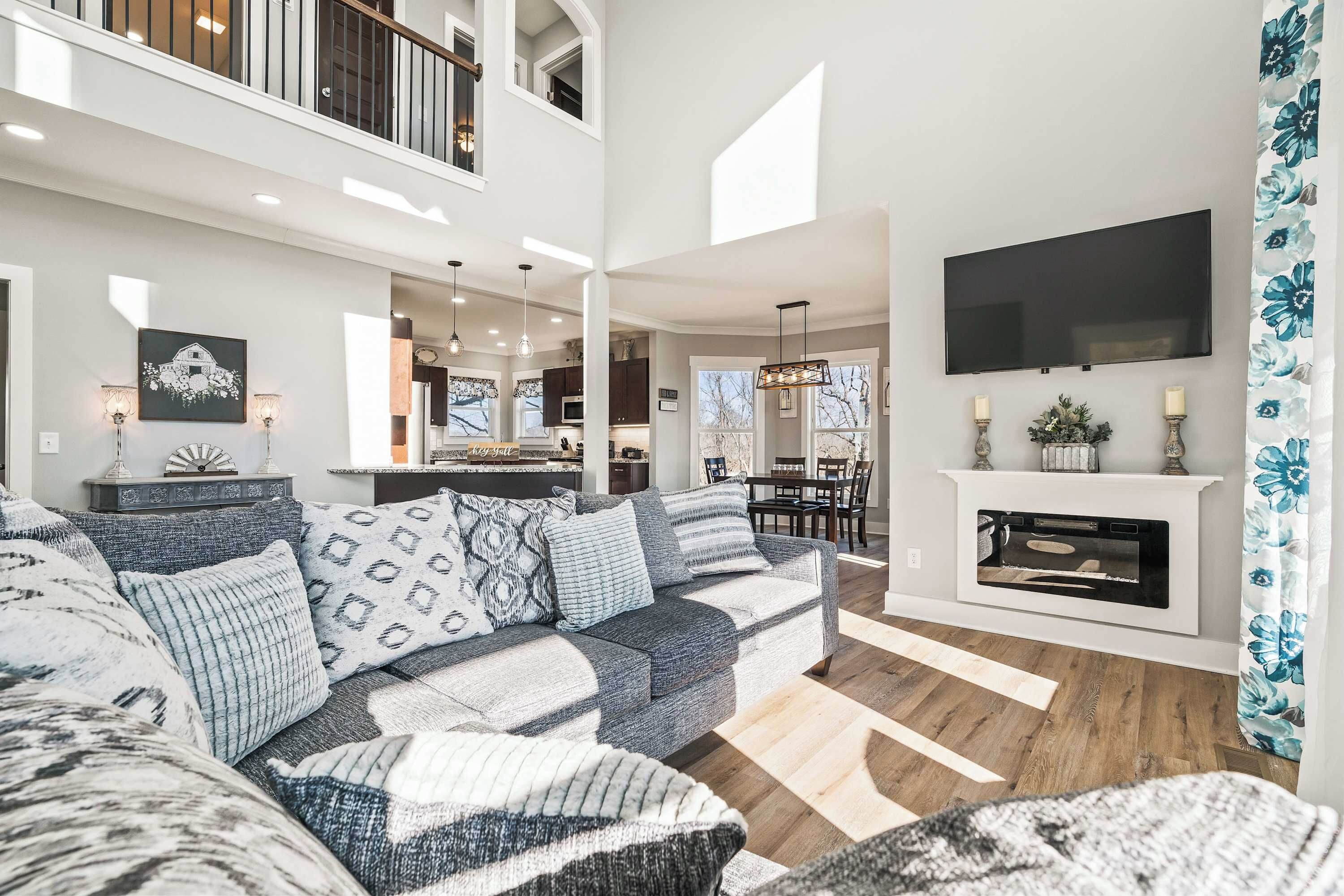 A spacious living room with a large sectional sofa, a fireplace, and a television mounted on the wall.