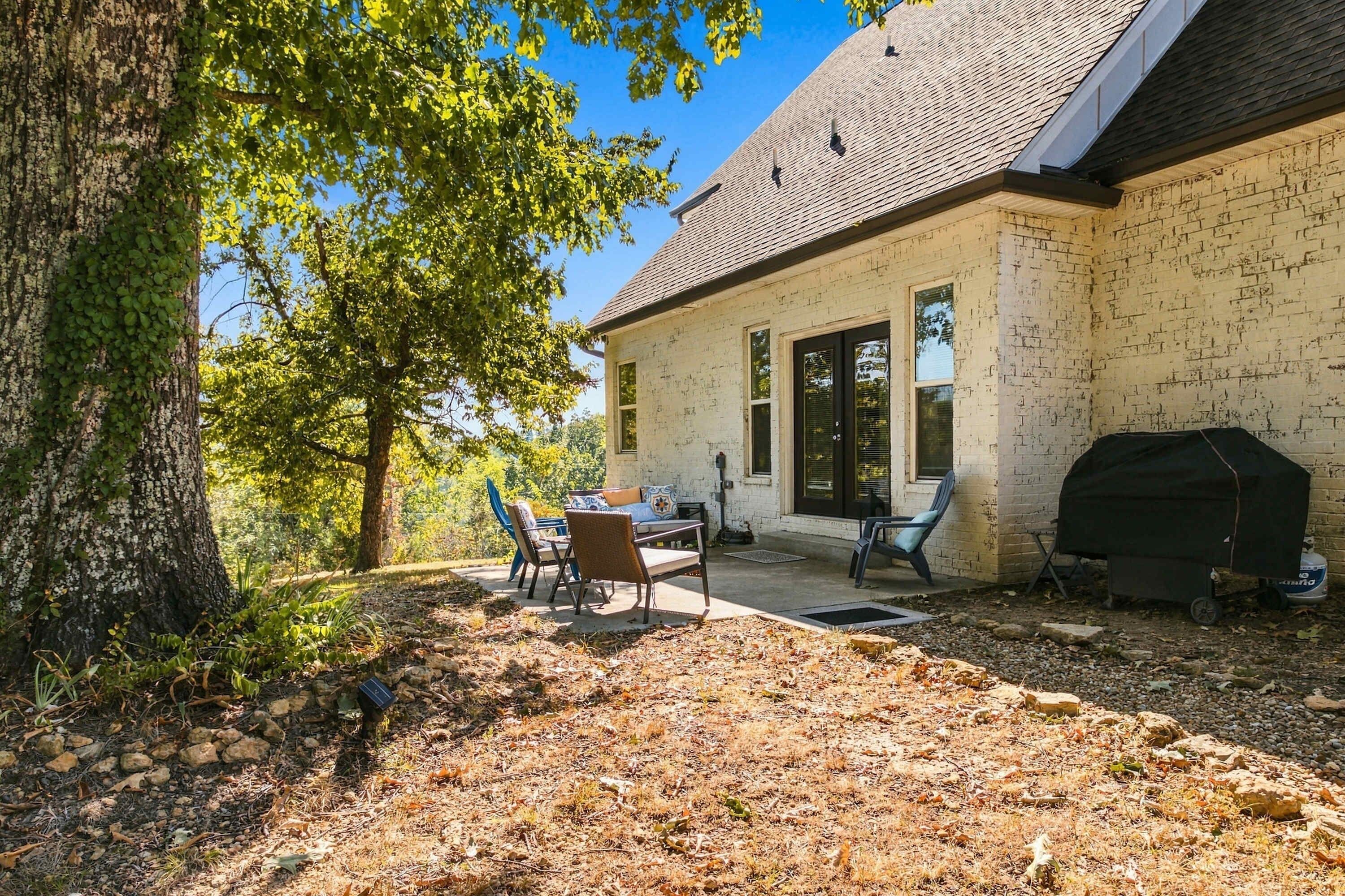 Una casa amb terrassa, mobiliari exterior i una barbacoa.
