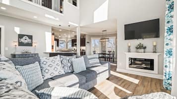 A spacious living room with a large sectional sofa, a fireplace, and a television mounted on the wall.
