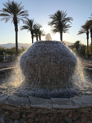 A water feature with a stone structure, surrounded by palm trees and a clear sky. - Stagecoach getaway Spacious Studio Guest room at Marriott Shadow Ridge (Palm Desert)