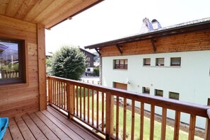 A wooden balcony with a view of a residential area, including a house with multiple windows and a tree. - 300m from ski slopes, 1st floor, balcony, 54m², Les Gets (Les Gets)
