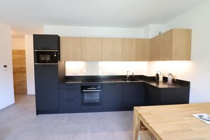 A modern kitchen with a built-in oven, a sink, and wooden cabinets. - 300m from ski slopes, 1st floor, balcony, 54m², Les Gets (Les Gets)