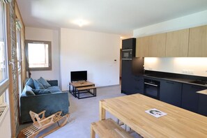 A compact living space with a kitchenette, a sofa, a small table, and a wooden bench. - 300m from ski slopes, 1st floor, balcony, 54m², Les Gets (Les Gets)
