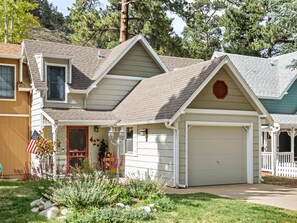 A two-story house with a garage, a front porch, and a small garden with rocks and plants. - River Front Escape, 3 Bedrooms on River, Quite area (Estes Park)