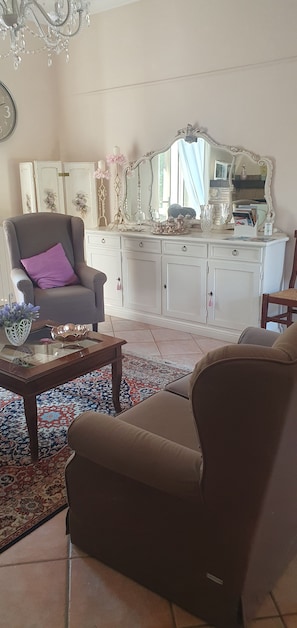 A living room with a sofa, armchair, coffee table, and a decorative mirror. - Located near the Marmore Falls, Villa Maria welcomes you to the Umbrian hills (Umbria)
