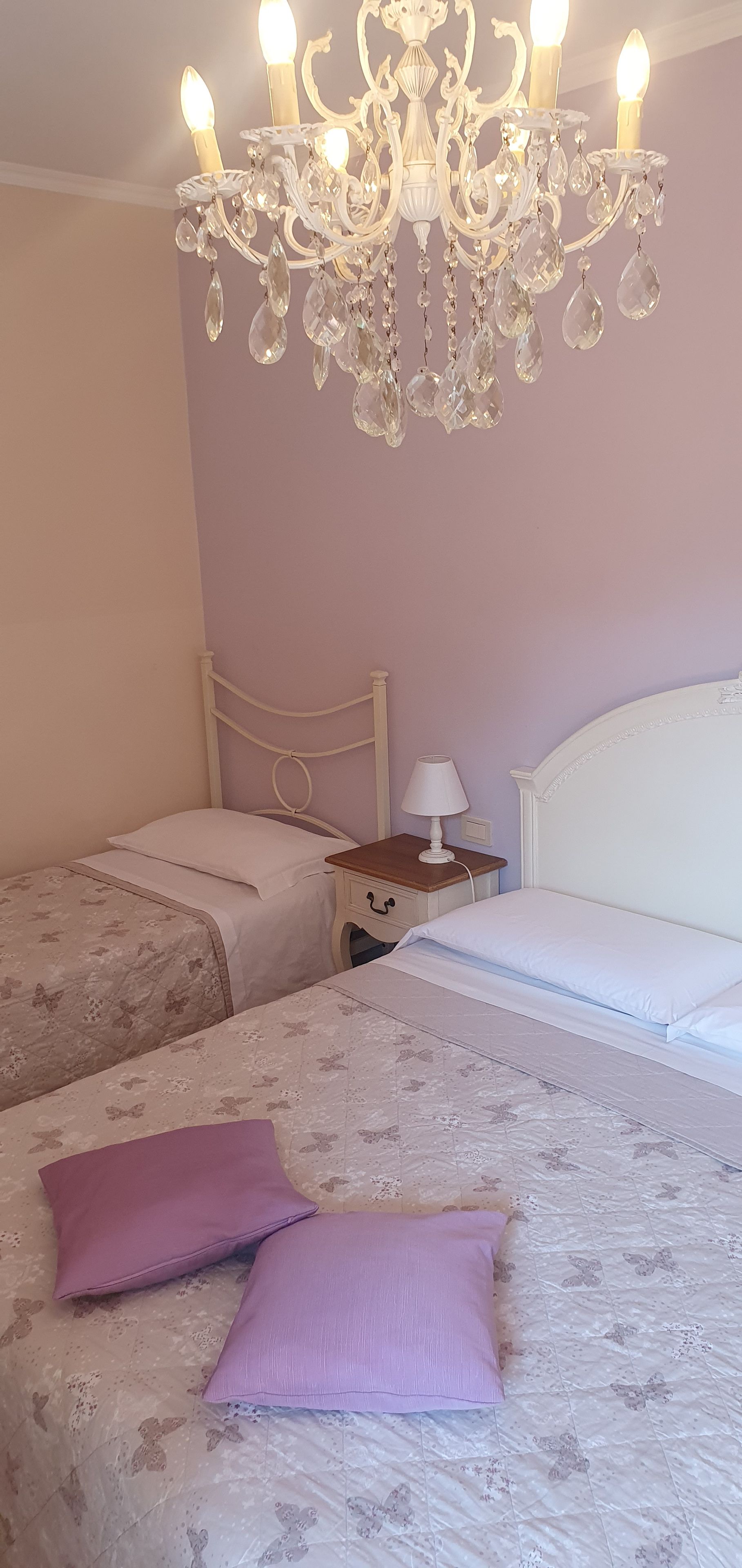 Una camera da letto con due letti, un lampadario e un comodino con una lampada.