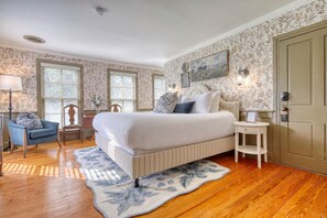 Une chambre à coucher avec un grand lit, une chaise, une table de chevet et une porte.