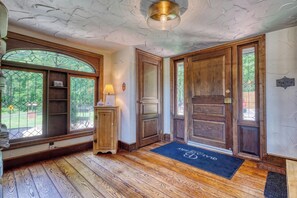 A wooden-floored entryway with a door, a window with a stained glass design, and a wooden cabinet.