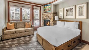 A bedroom with a large bed, a sofa, a fireplace, and framed pictures on the wall. - Mountain Escape Near Breckenridge Ski Resort & Main Street (Breckenridge)