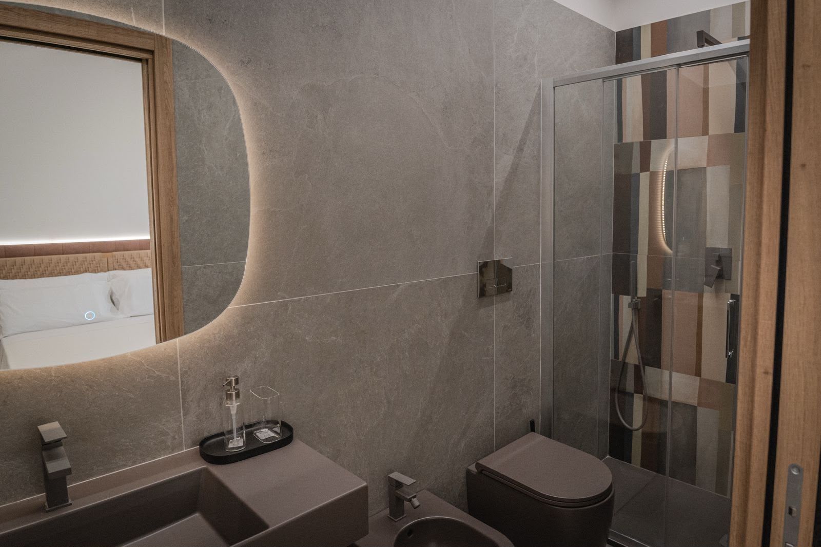 Une salle de bain moderne avec un miroir incurvé, une cabine de douche et des toilettes.