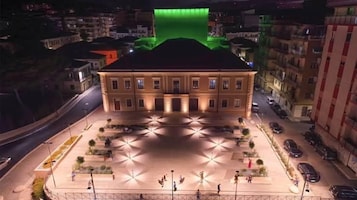 Un edificio con fachada simétrica, un patio central y una calle frente a él.