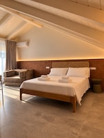 Un dormitorio moderno con una cama grande, un sofá y un taburete pequeño y redondo.