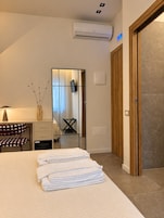 Habitación de hotel con una cama, un escritorio, un espejo y un equipo de aire acondicionado.