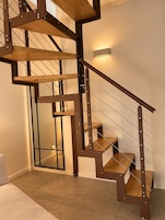Una escalera moderna con detalles de madera y barandales de metal.