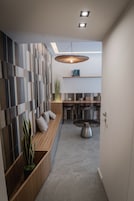 Un interior moderno con una zona de estar, una mesa de comedor con sillas y una lámpara colgante.