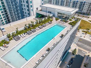 A rooftop swimming pool with sun loungers and a parking area. - The Louie - Luxe 1BR Condo DT w/ Rooftop Pool, Gym (Orlando)
