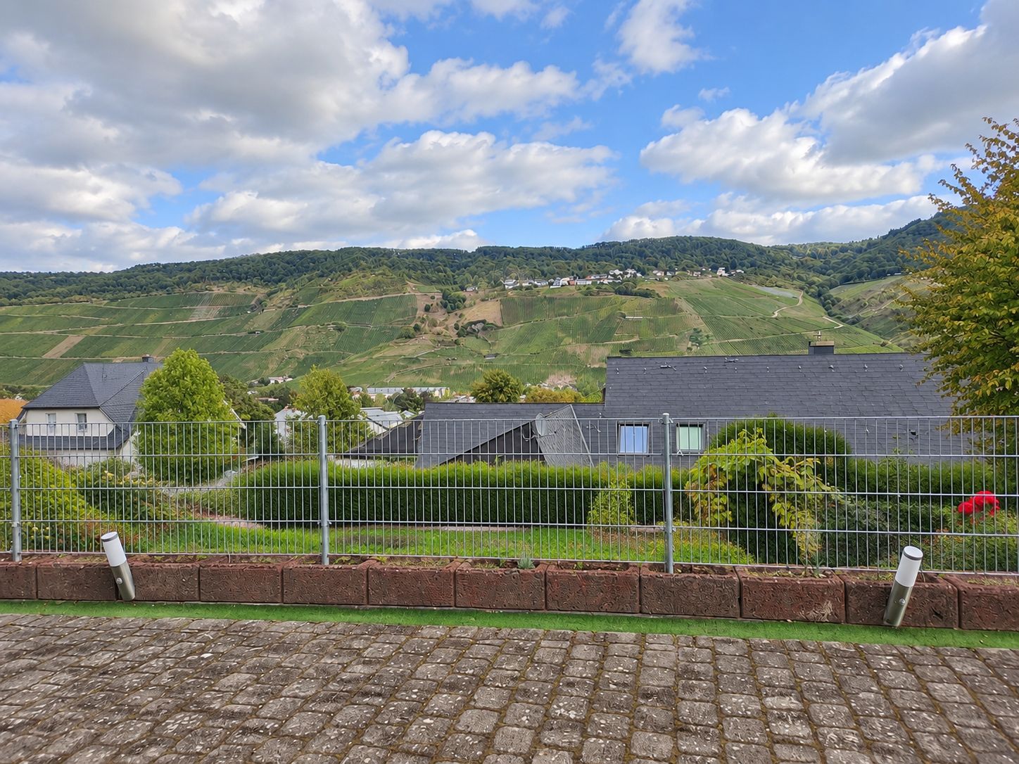 A rural landscape with houses, a fence, and a paved area.