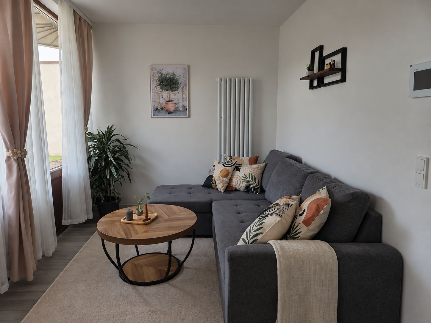 A modern living room with a grey sofa, a round wooden coffee table, and a potted plant.